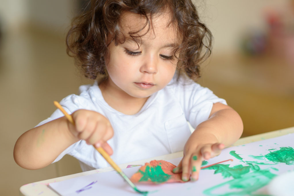 young girl painting with green paint
