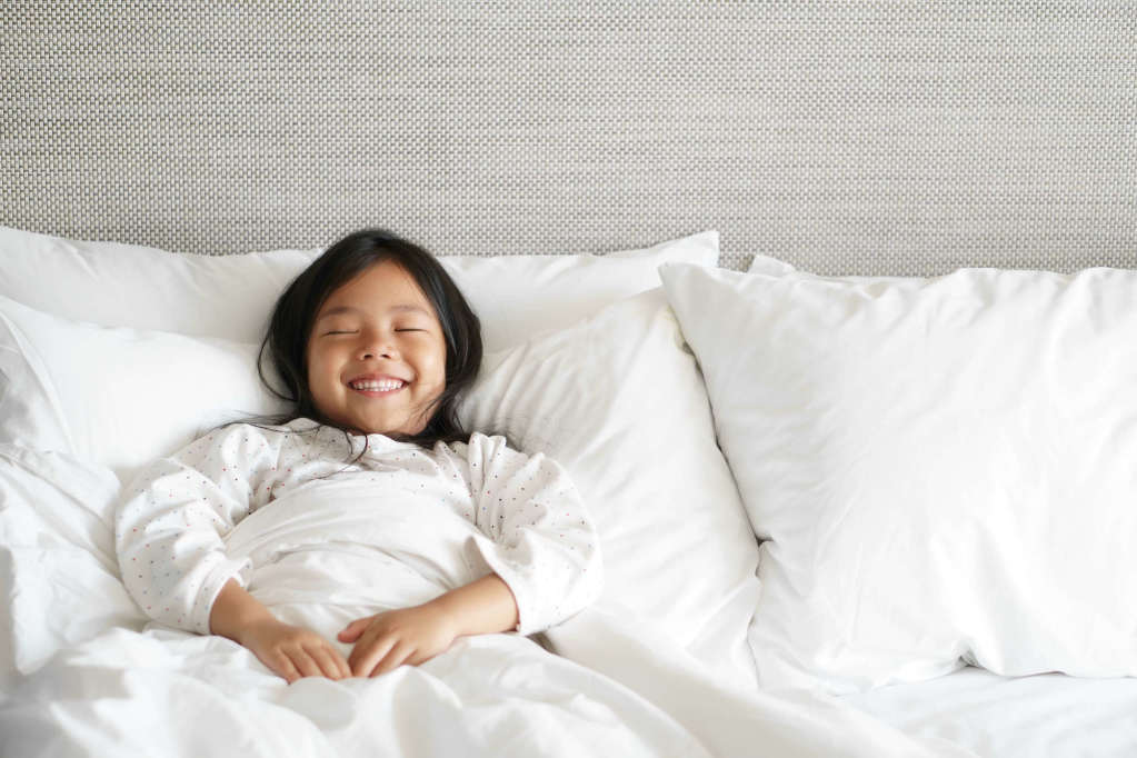 young asian girl smiling in bed meditating