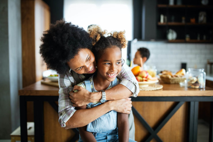 positive mom hugging happy daughter in kitchen